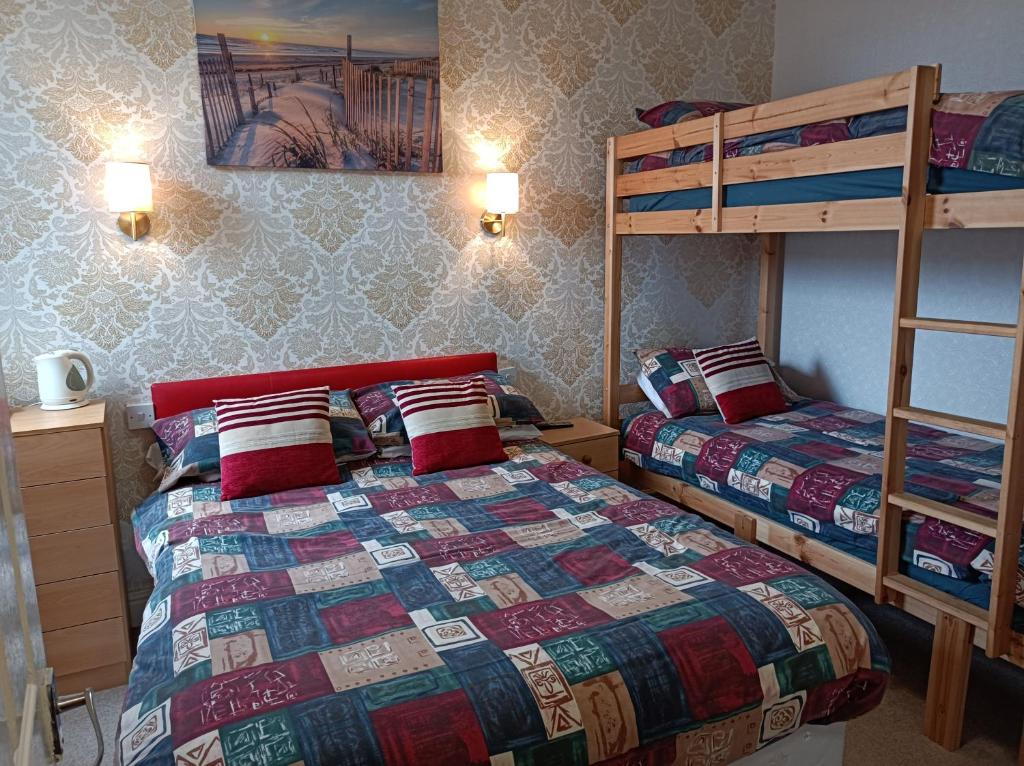 a bedroom with two beds and a bunk bed at Stafford House in Blackpool