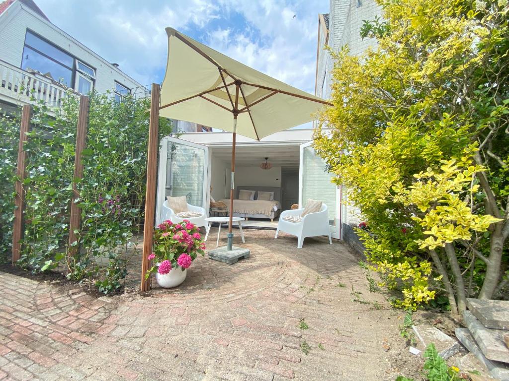 un patio con sombrilla, mesa y sillas en Emma Lodge Zandvoort en Zandvoort