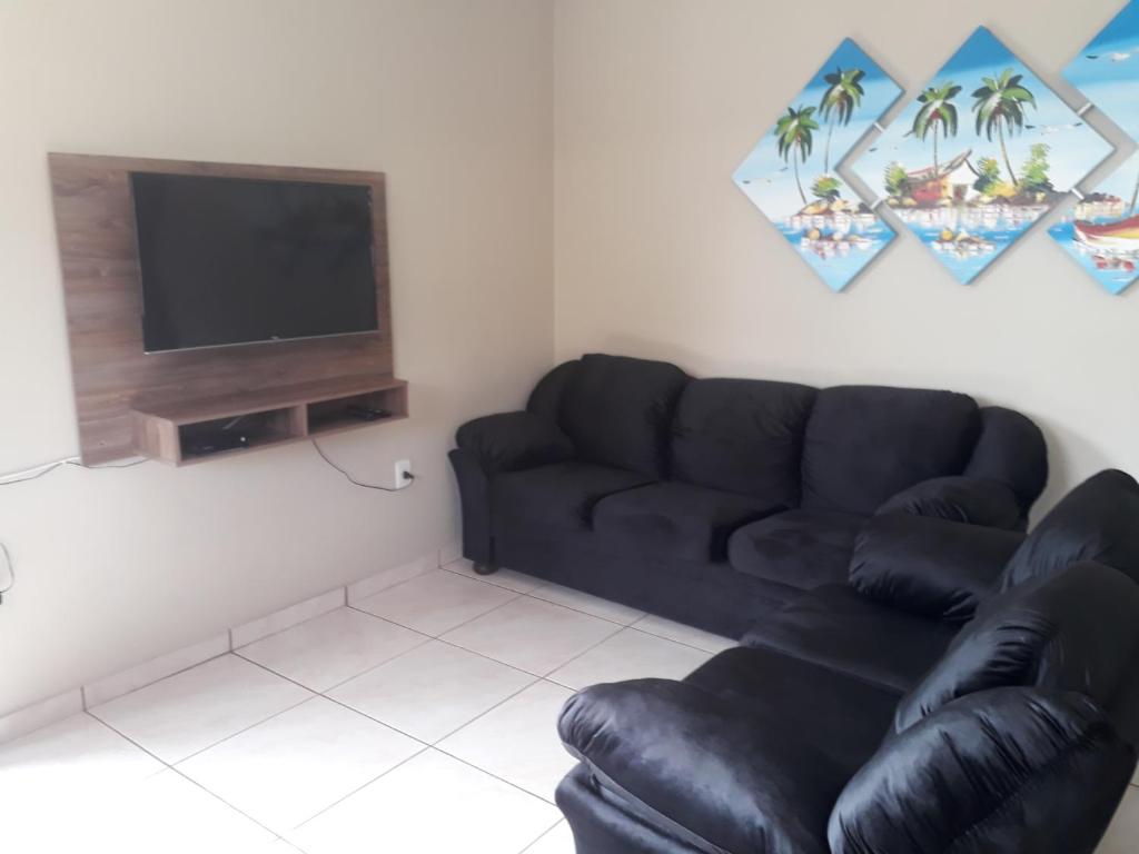 a living room with a black couch and a television at Aluguel casa Bombinhas in Bombinhas