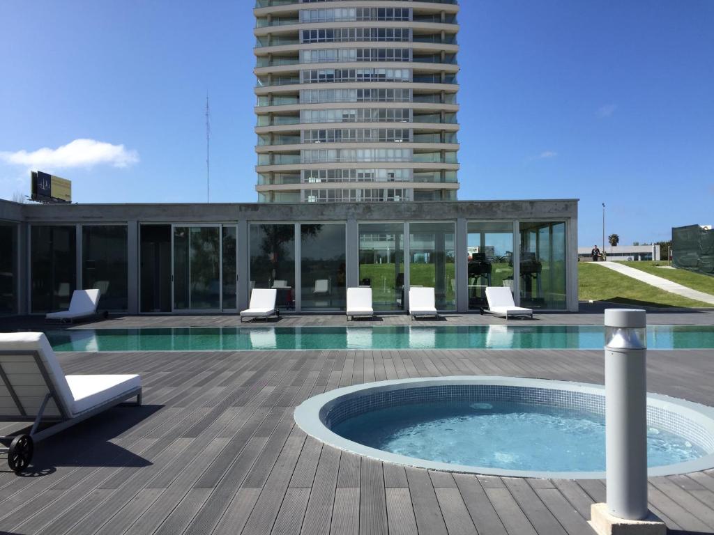 a swimming pool with chairs and a building at Faros de Carrasco Apartments in Montevideo