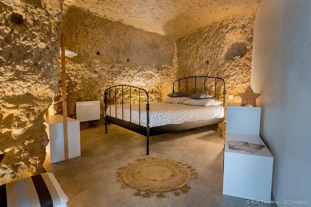 ein Schlafzimmer mit einem Bett in einem Steinzimmer in der Unterkunft La cavée du coteau, petit cocon troglodytique in Vouvray