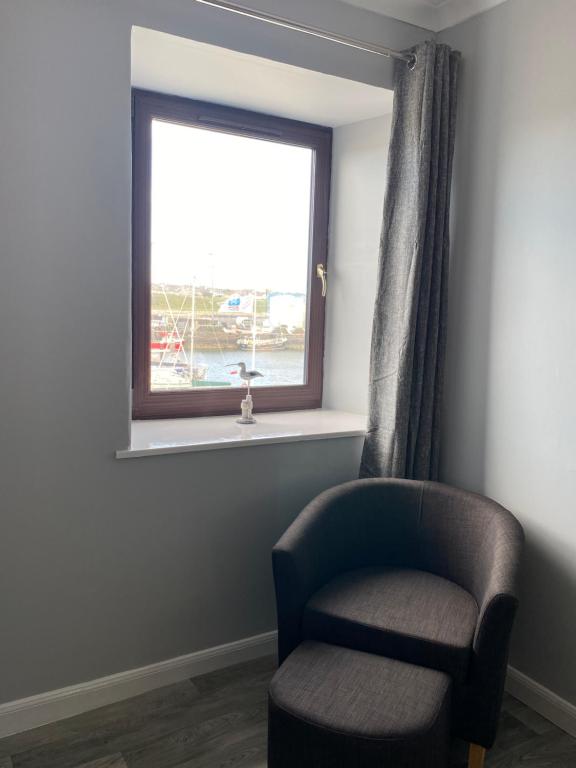 una silla en una habitación con ventana en Sea Breeze Apartment Wick en Wick