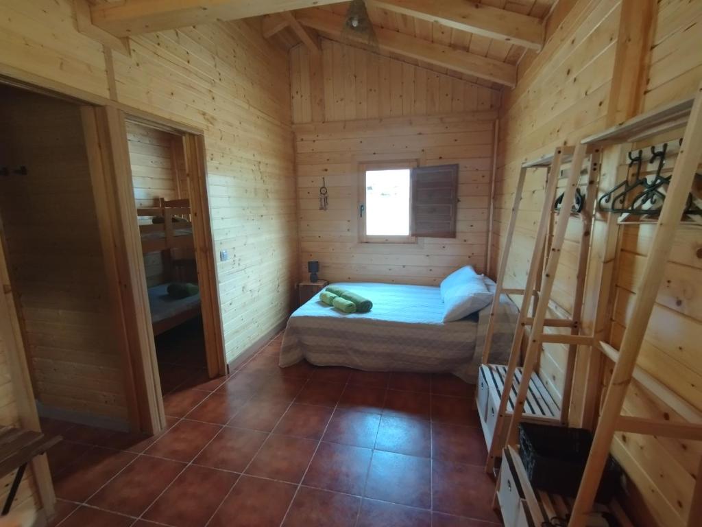 Habitación con cama en una cabaña de madera en CAMPING LA ZARAPICA - Palacios del Sil en Palacios del Sil