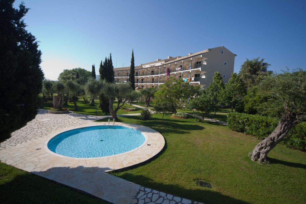 a swimming pool in a park with a building in the background at Delfinia Hotel in Moraitika