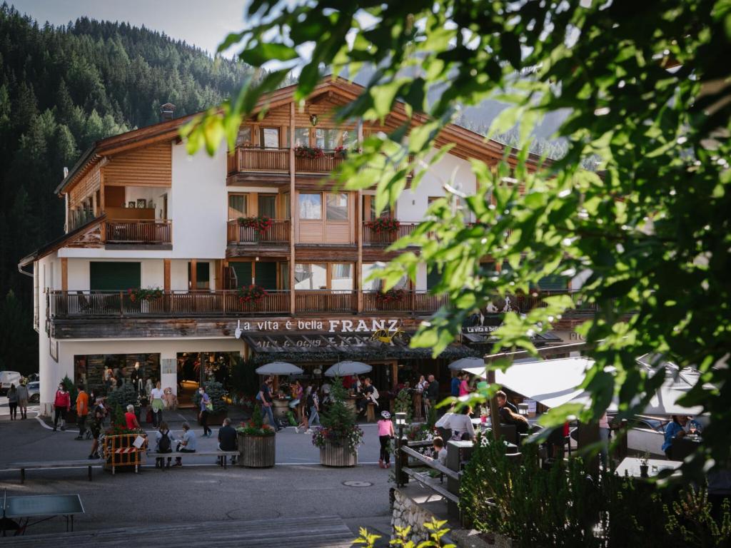 a large building with people sitting outside of it at Apartments DA LA VEDLA Flats in San Cassiano