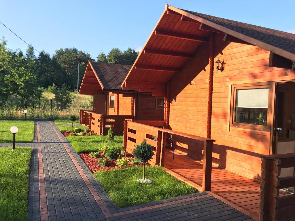 Cabaña de madera con porche y pasarela. en Ośrodek u Antosia na Mazurach en Narty