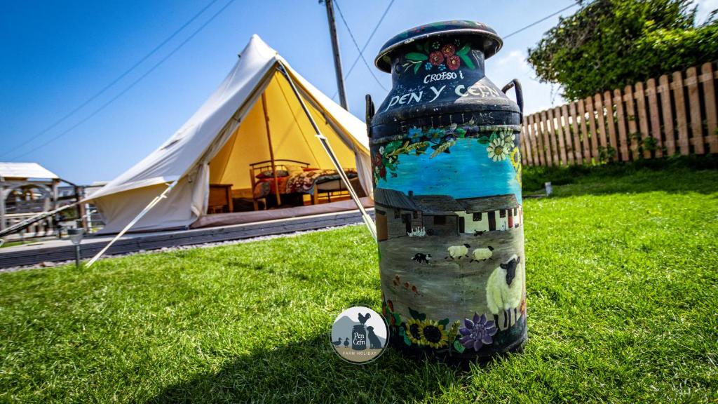 - une bouteille dans l'herbe à côté d'une tente dans l'établissement Yr Wyddfa Bell Tent - Pen Cefn Farm, Abergele, Conwy, à Abergele