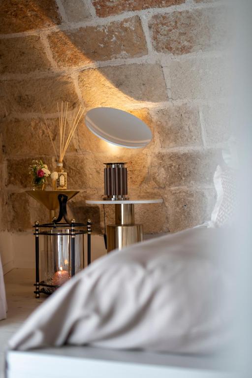 a bedroom with a stone wall with a bed and a lamp at New Dimora Valmar in Polignano a Mare