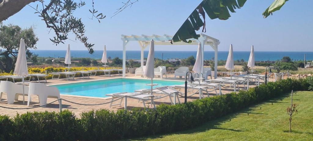 a pool with chairs and umbrellas next to the ocean at B&B Giglio Marino in Salve