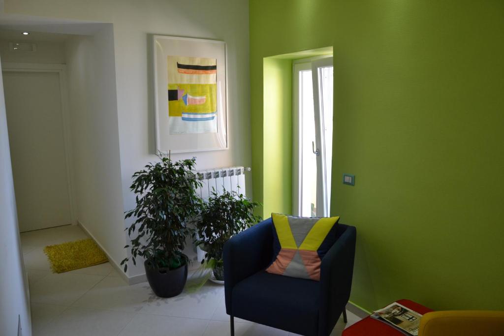 a living room with a blue chair and green walls at Terra Murata Boutique b&b in Procida