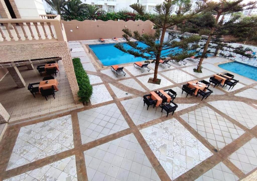 una vista sul tetto di una piscina con tavoli e sedie di Agyad Maroc Appart-Hotel ad Agadir