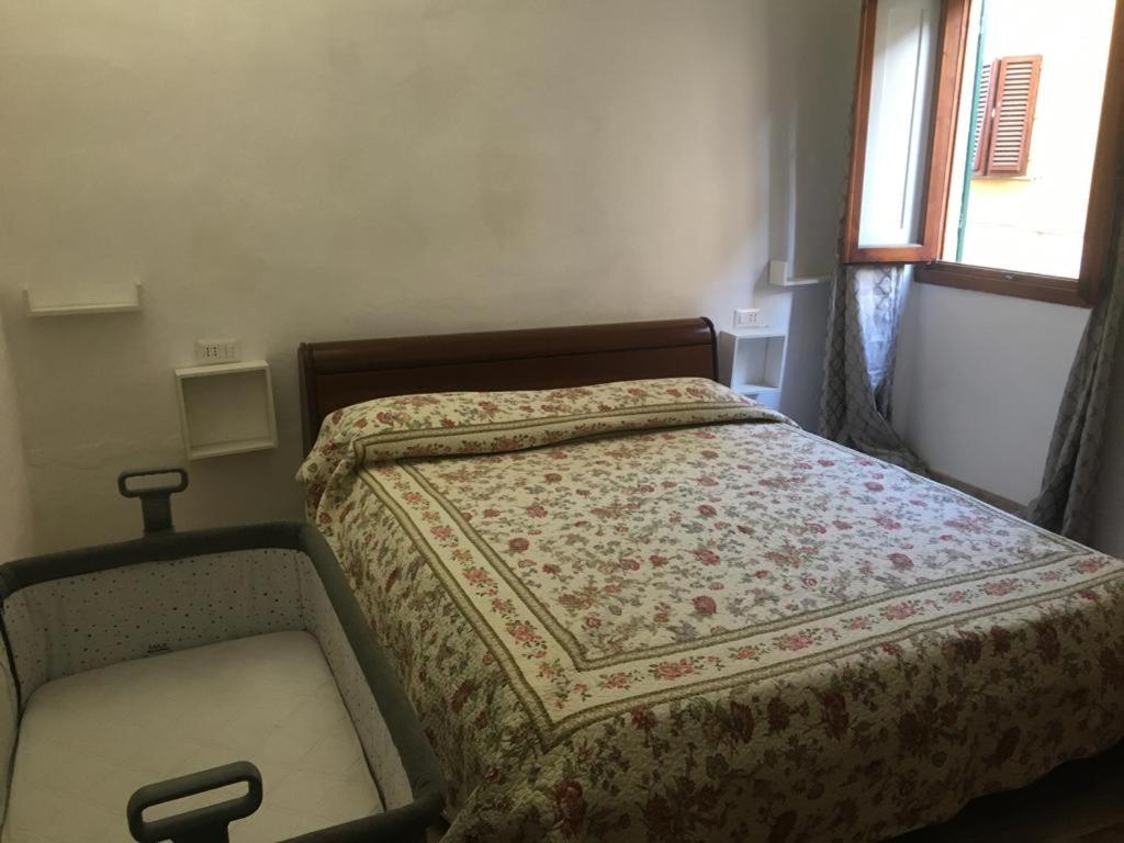 un pequeño dormitorio con una cama con una manta. en Terrazza il canto al romano, en Figline Valdarno
