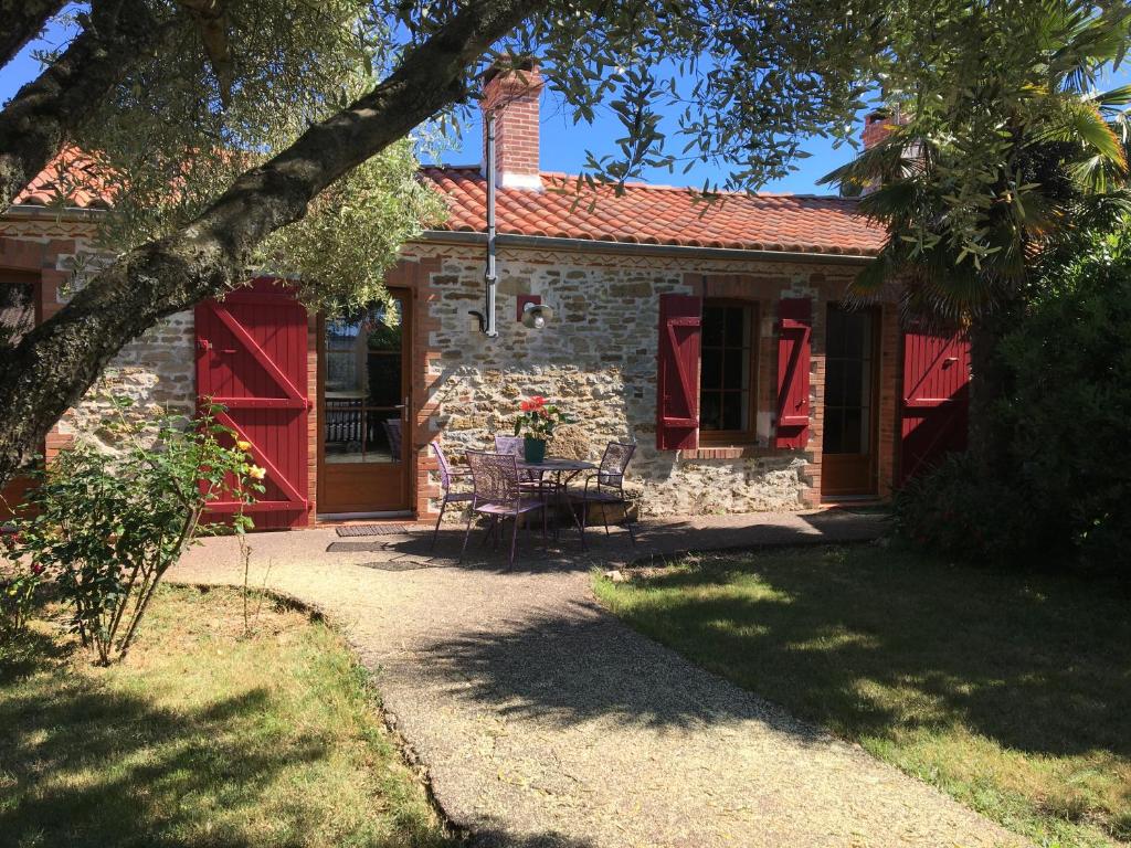 Casa de piedra con puertas rojas y patio en LE CLOS DE LA VINIERE, en Jard-sur-Mer