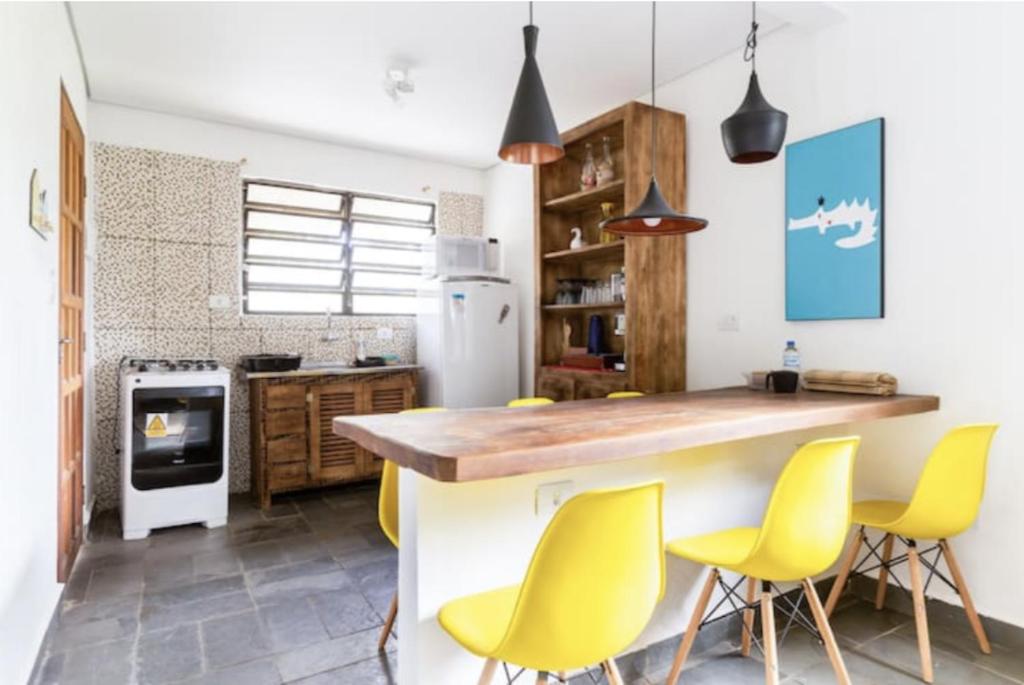 a kitchen with yellow chairs and a kitchen island at Casa Litoral Sul de São Paulo, Peruibe in Itariri