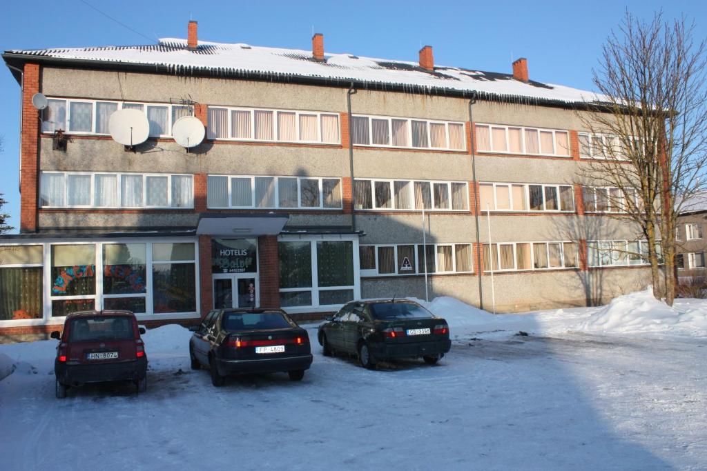 tres autos estacionados frente a un edificio en la nieve en Balvi Hotel, en Balvi