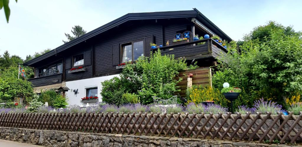a black and white house with a fence and flowers at Haus Harzer Bergblick all inklusiv in Bad Lauterberg