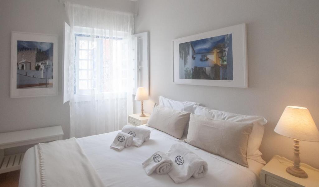 a bedroom with a white bed with towels on it at Casa da Travessa - Óbidos in Óbidos