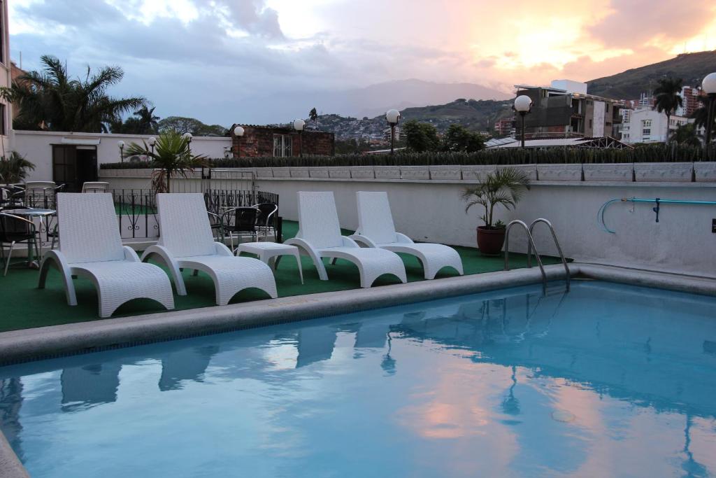 una fila di sedie bianche accanto alla piscina di Hotel San Fernando Real a Cali