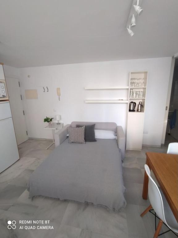 Biały salon z łóżkiem i stołem w obiekcie Ático-Duplex Las Palmeras w mieście Conil de la Frontera