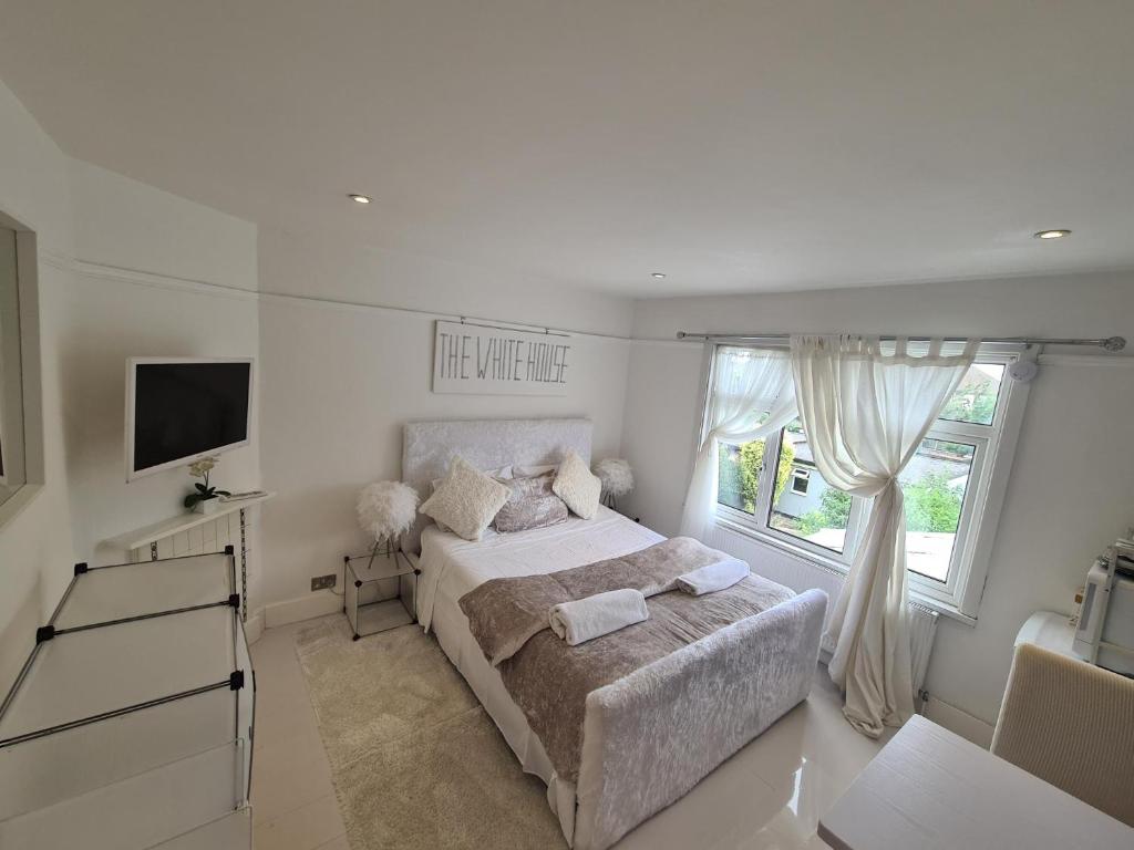 a white bedroom with a bed and a window at The White House in Waltham Cross