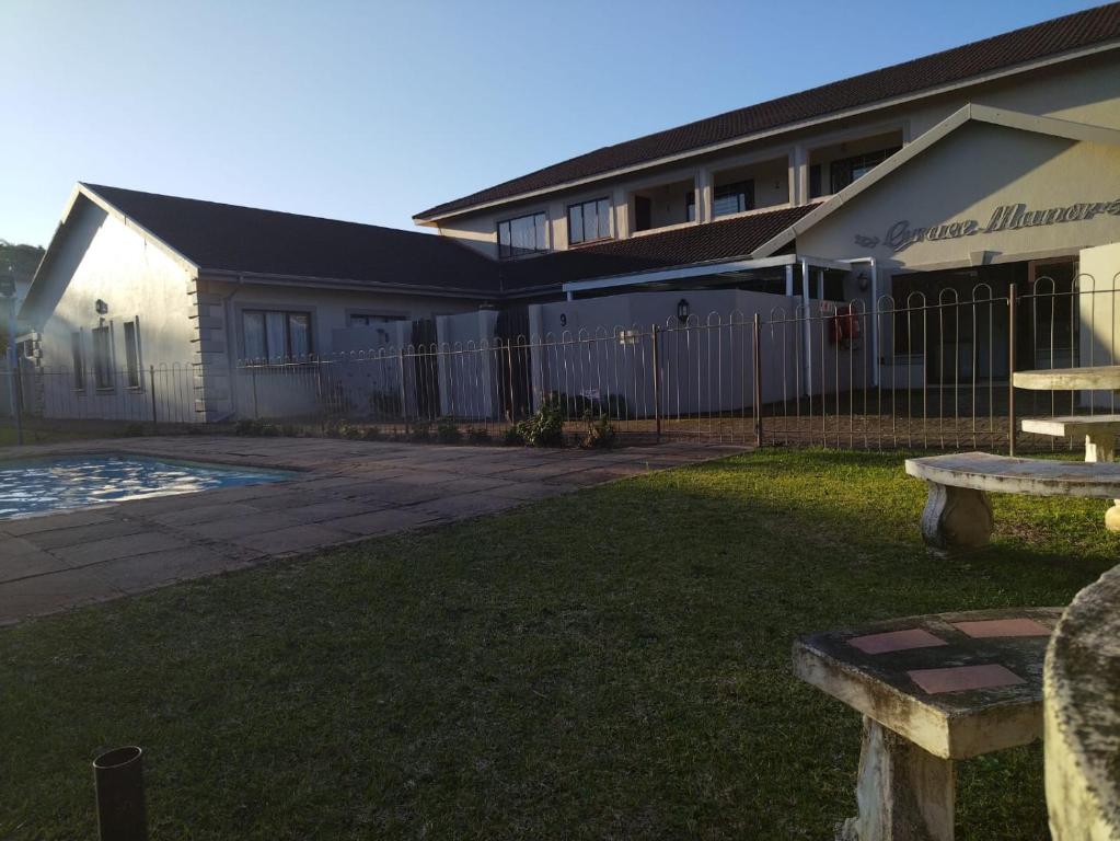 a building with a fence and a bench in a yard at Grace Manor in Port Edward
