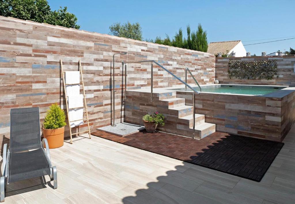 un patio con una piscina con una pared de ladrillo en Villa Ébano, en Conil de la Frontera