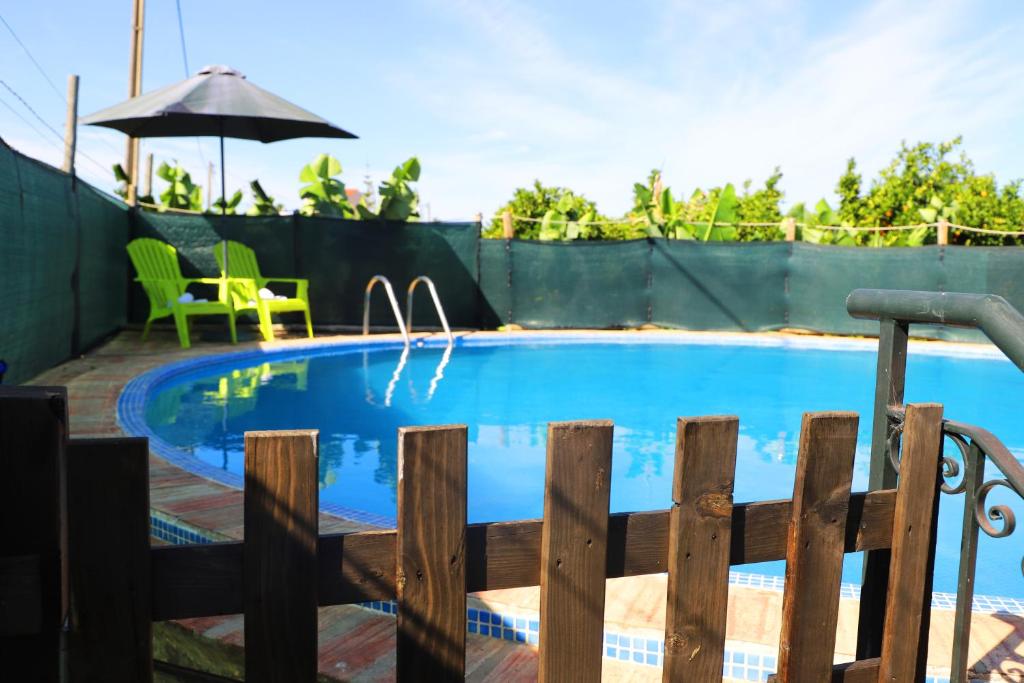 una piscina con una valla y una sombrilla en O Quadradinho, en Tavira