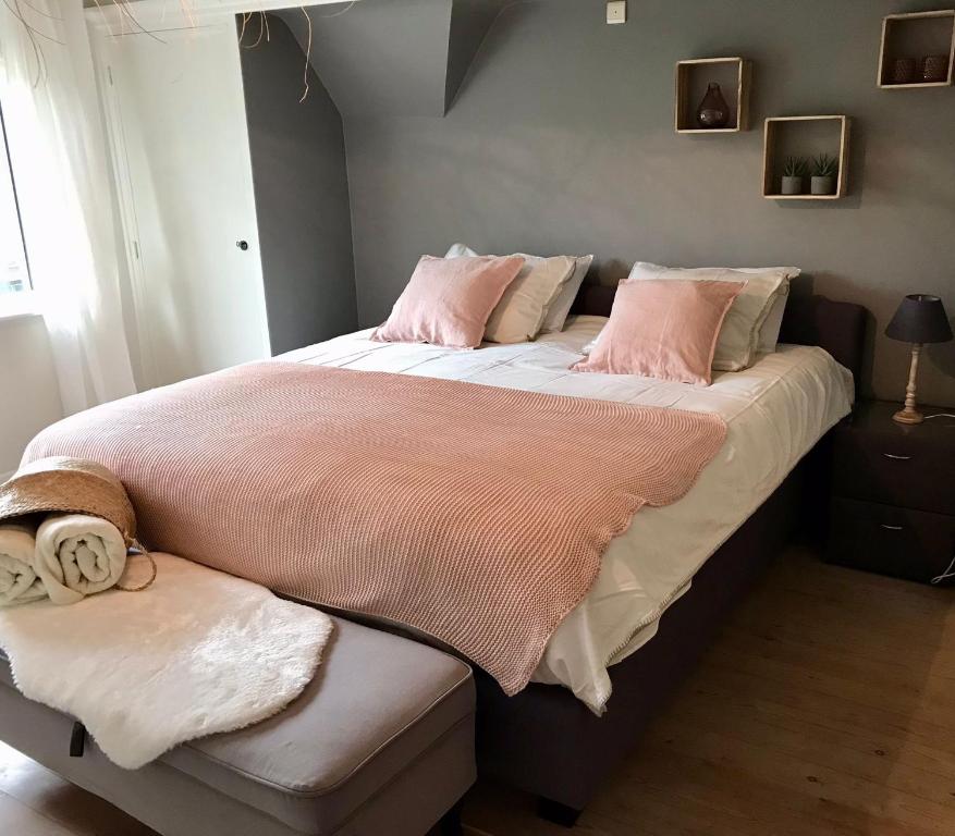 a bedroom with a large bed with pink blankets and pillows at De Bijenkorf in Damme