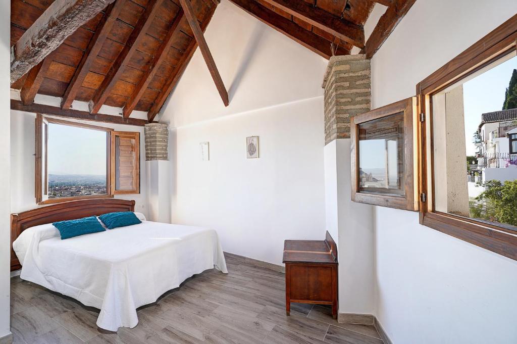 a bedroom with a bed and two windows at LM Casa ALBAYCIN in Granada