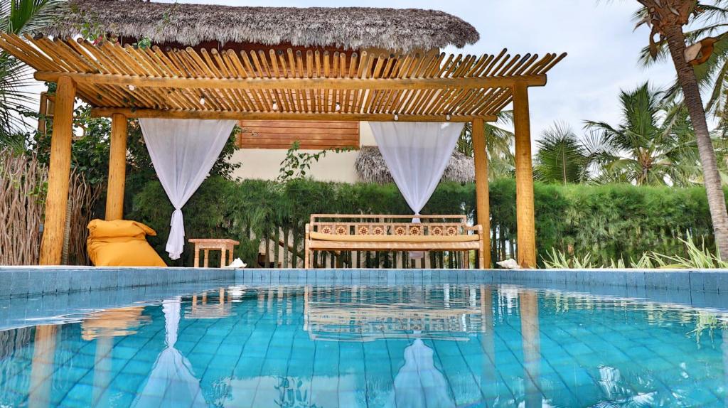 a swimming pool with a gazebo next to a resort at Vila Gará Kite House - Ilha do Guajiru in Itarema