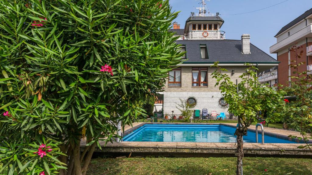 basen przed budynkiem z wieżą zegarową w obiekcie Villa Cecilia - Casa marinera con piscina y jardín w mieście Colindres