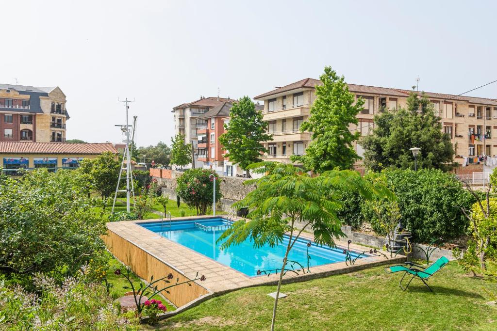basen w ogrodzie z budynkami w tle w obiekcie Villa Cecilia - Casa marinera con piscina y jardín w mieście Colindres