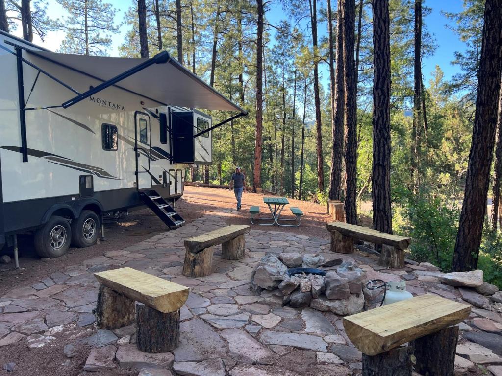 uma caravana com uma mesa de piquenique e bancos na floresta em Luxury Glamper Retreat 14 Forest Site em Payson