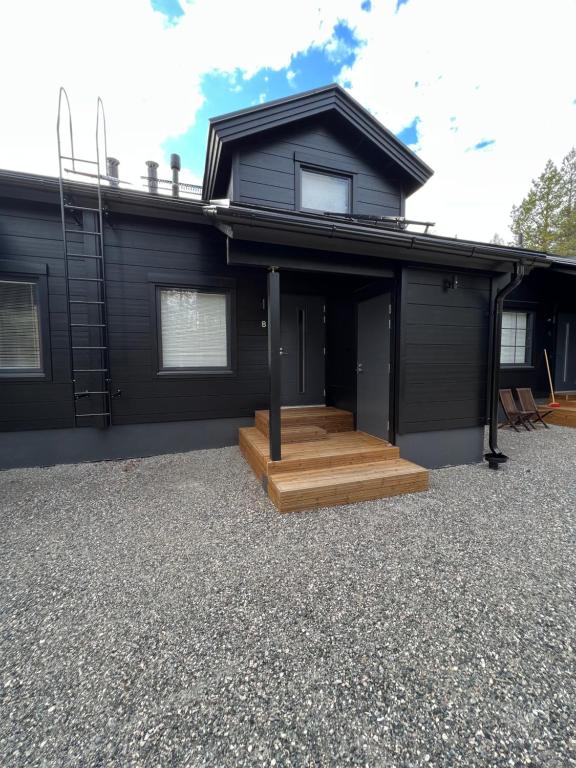 una casa nera con portico in legno e scala di Hankatie 20B a Kittilä