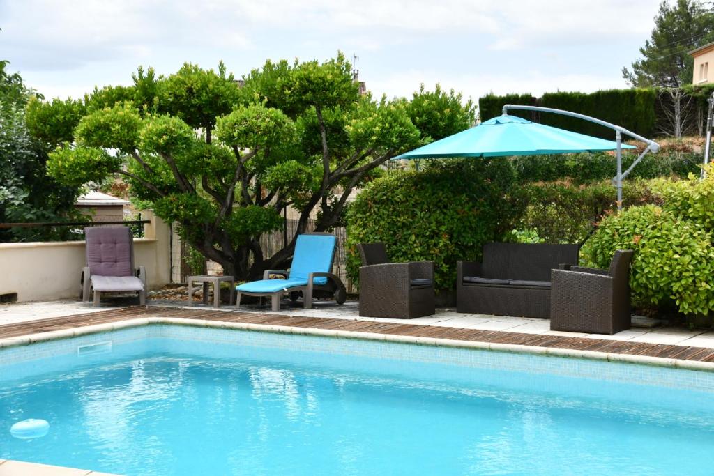 a swimming pool with chairs and an umbrella at L’ocabée in La Tour-dʼAigues