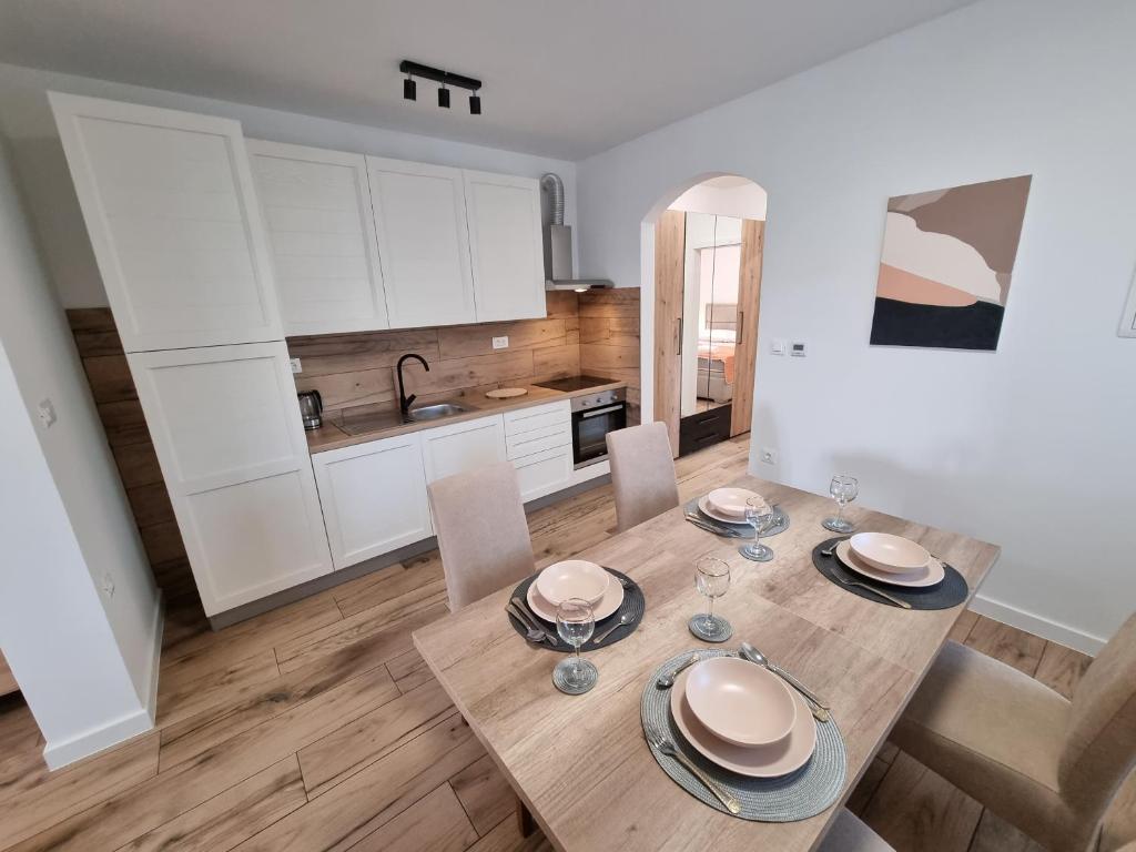 a kitchen with a wooden table with plates and wine glasses at Apartman Lovre in Zadar