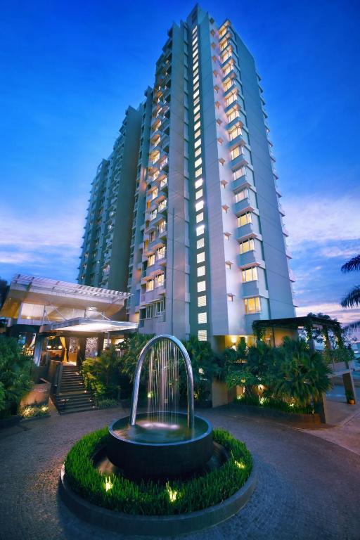 een groot gebouw met een fontein ervoor bij Golden Tulip Balikpapan Hotel & Suites in Balikpapan