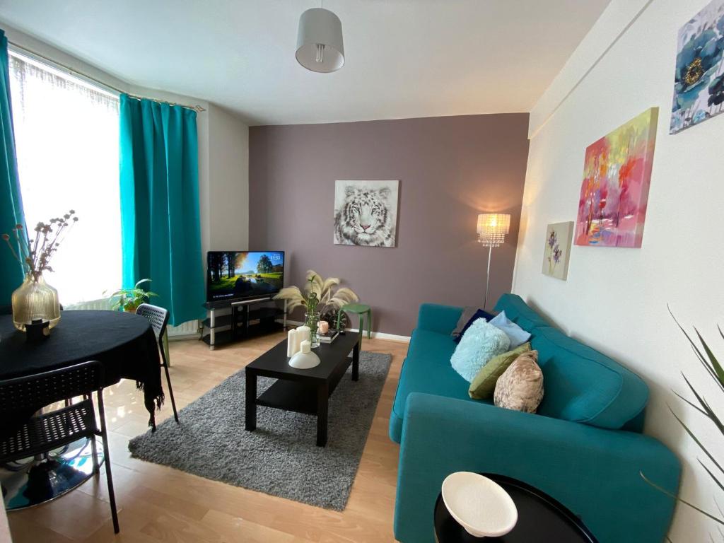 a living room with a blue couch and a piano at Cheerful 4 bedrooms home 8 mn to train station in Plumstead