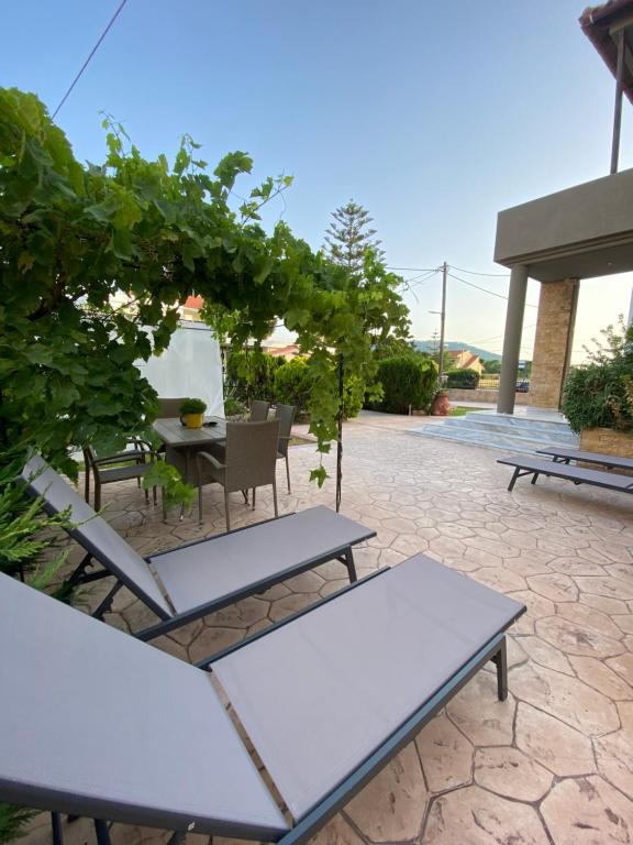 a patio with a table and chairs and vines at Eva's Garden House in Ialyssos
