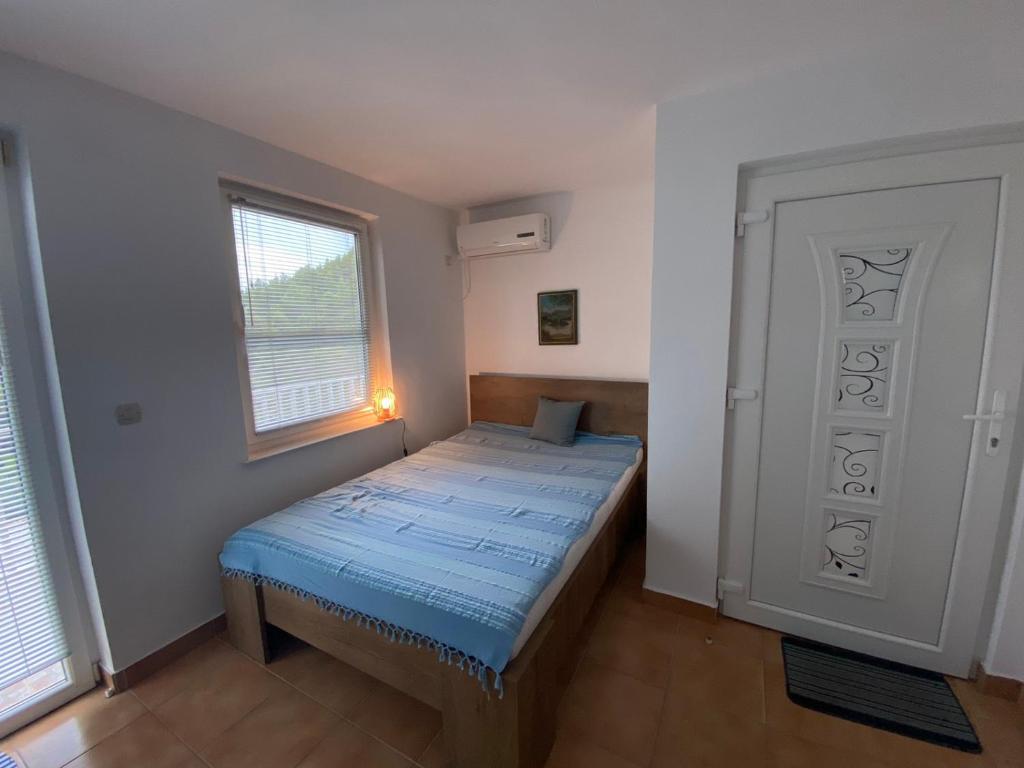 ジュリャナにあるApartman Anaの青いベッドと窓付きの小さなベッドルームが備わります。