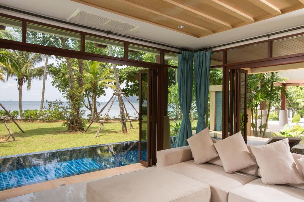 a living room with a white couch and a view of the ocean at Amatapura Beachfront Villa 14, SHA Certified in Ao Nam Mao