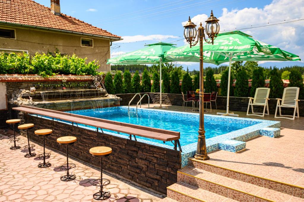 a swimming pool with a table and chairs and an umbrella at Guest House Dinaya in Dobrinishte