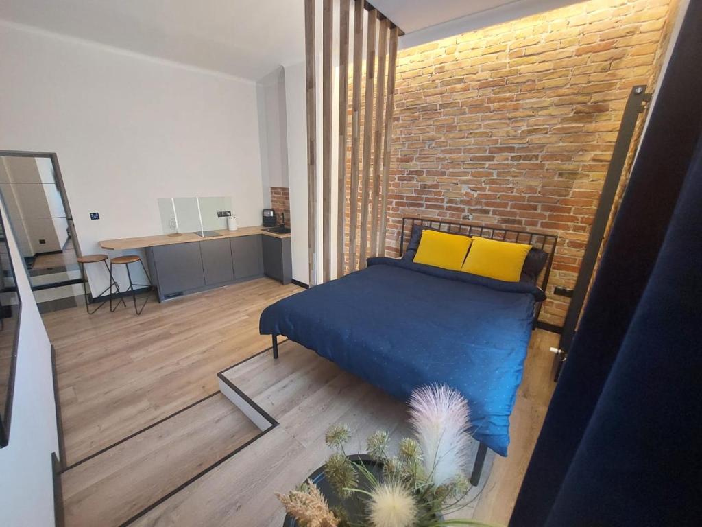 a bedroom with a blue bed and a brick wall at Sparrow Apartment in Świnoujście