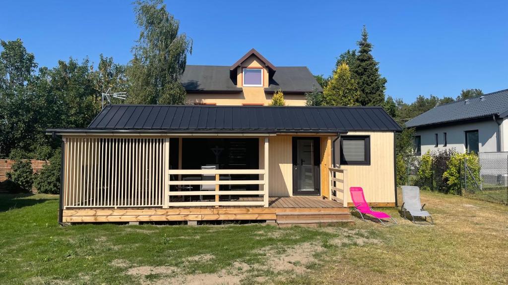 a tiny house with a deck in a yard at Domki przy Sosnowej in Ostrowo