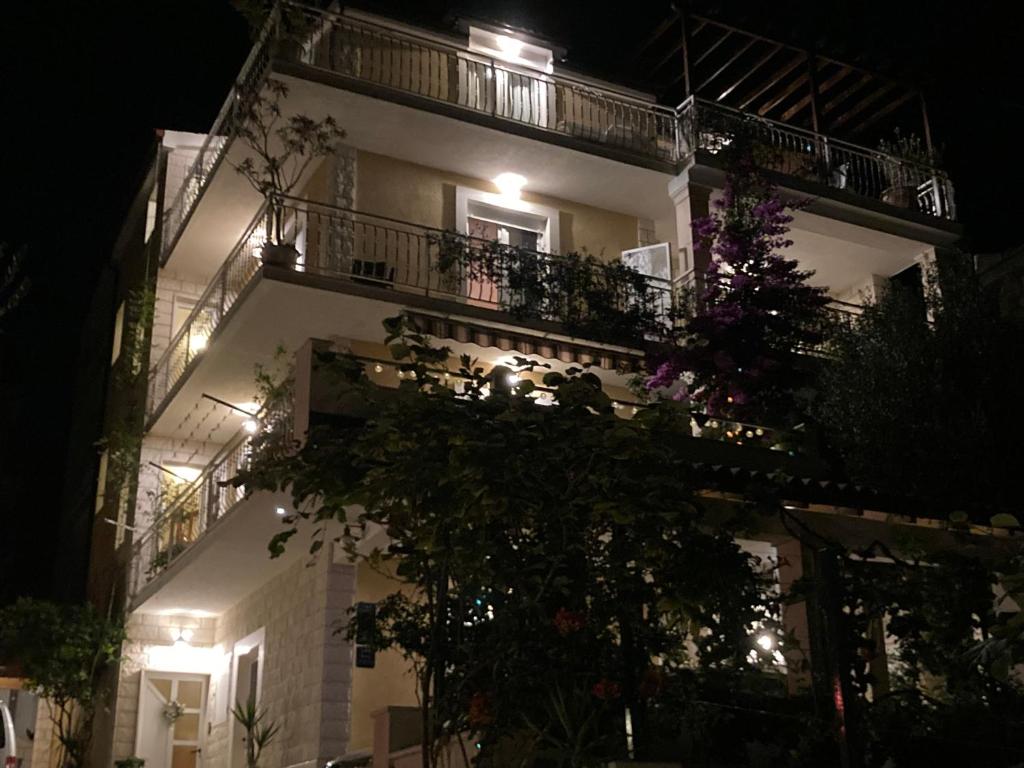 a tall white building with a balcony at night at Guest house Adria in Dugi Rat