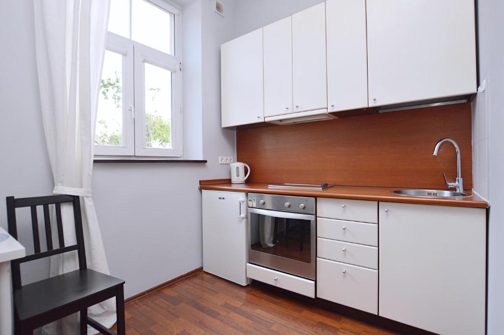 a kitchen with white cabinets and a sink and a stove at Studio Sopot Sklodowskiej-Curie in Sopot