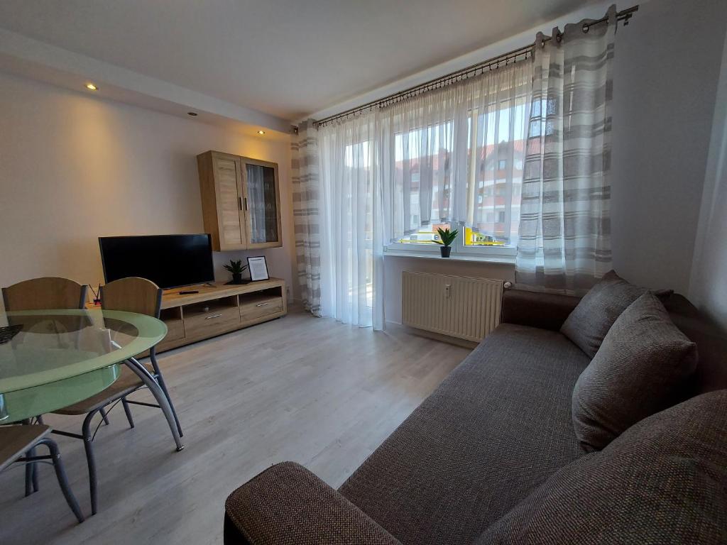 ein Wohnzimmer mit einem Sofa und einem Glastisch in der Unterkunft Apartament Wenedów in Koszalin
