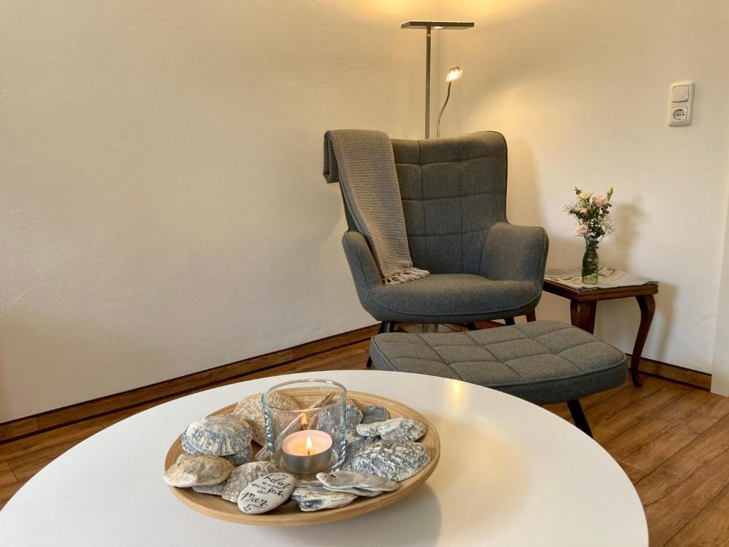 uma sala de estar com uma cadeira e uma mesa com uma vela em Ferienhaus-Spatzenvilla em Lübeck