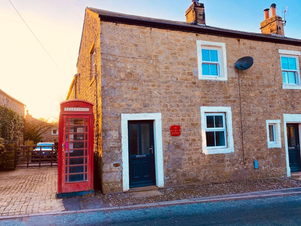 an old red phone booth in front of a brick building at Olde Post House, Rathmell - Settle in Settle