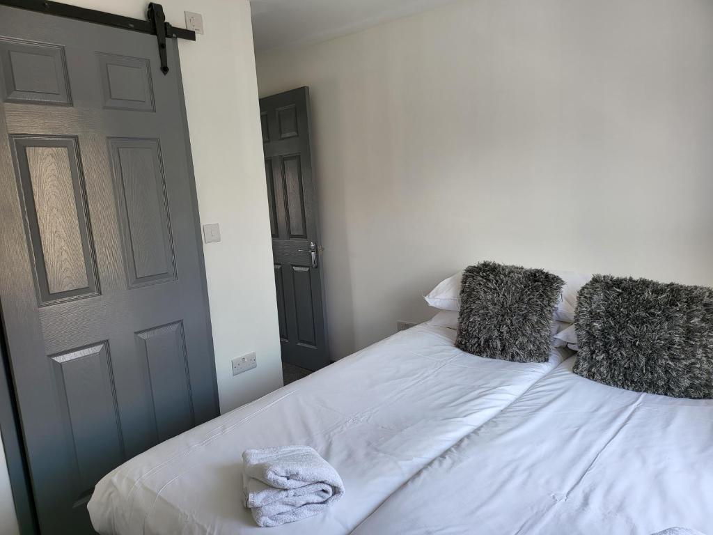 a bedroom with a bed with white sheets and pillows at Vetrelax Colchester 3bedroom house in Colchester